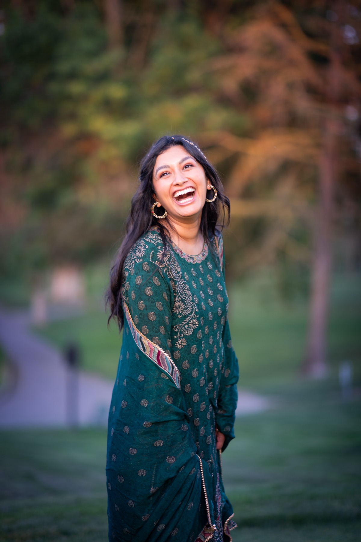 Woman laughing in a green suit at sunset